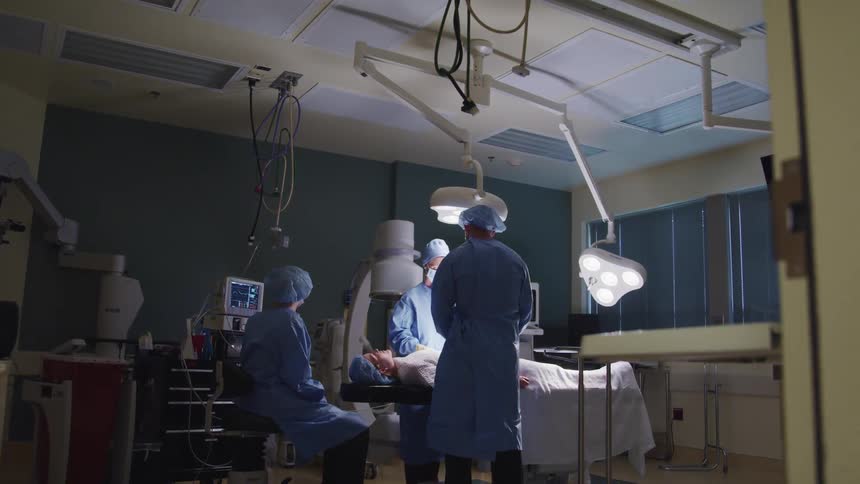 A medical team stands over a patient on an operating table