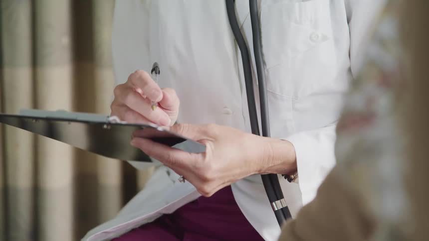 A doctor is writing on a clipboard