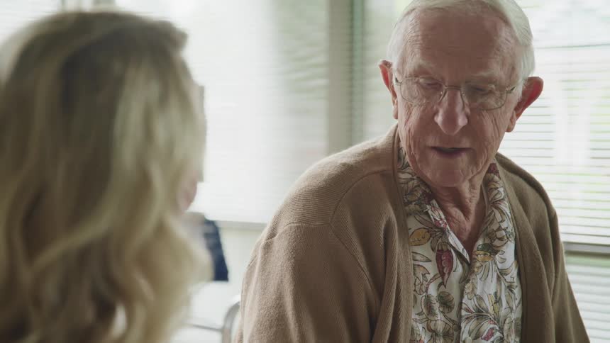 An elderly patient talks to a doctor in a hospital room
