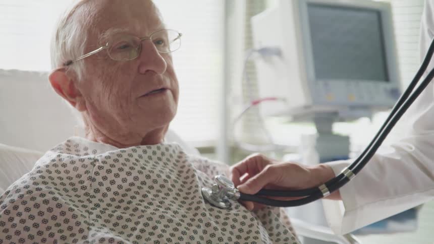 A doctor listens to the chest of an elderly patient with a stethoscope
