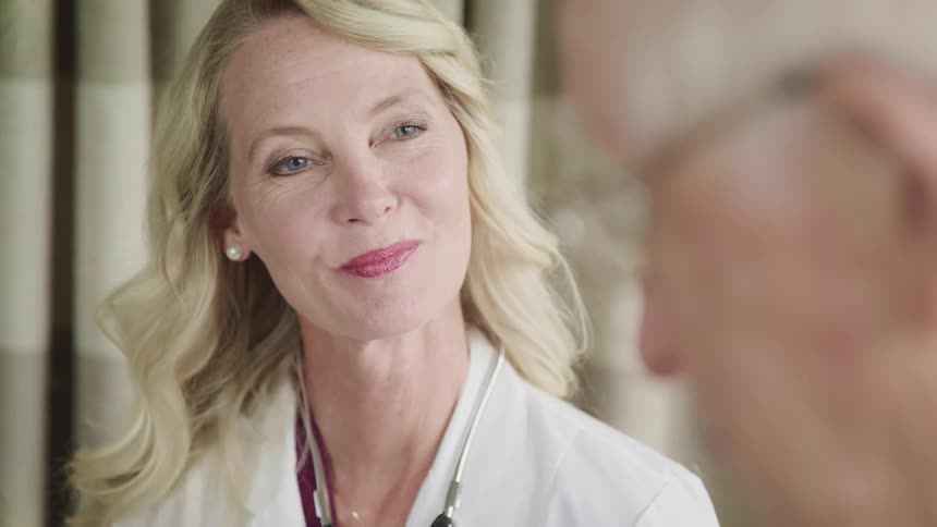 Male patient talks to a female doctor as she smiles and listens intently
