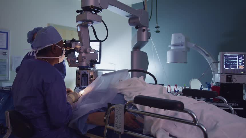 A doctor performs a procedure on a patient as a nurse stands by