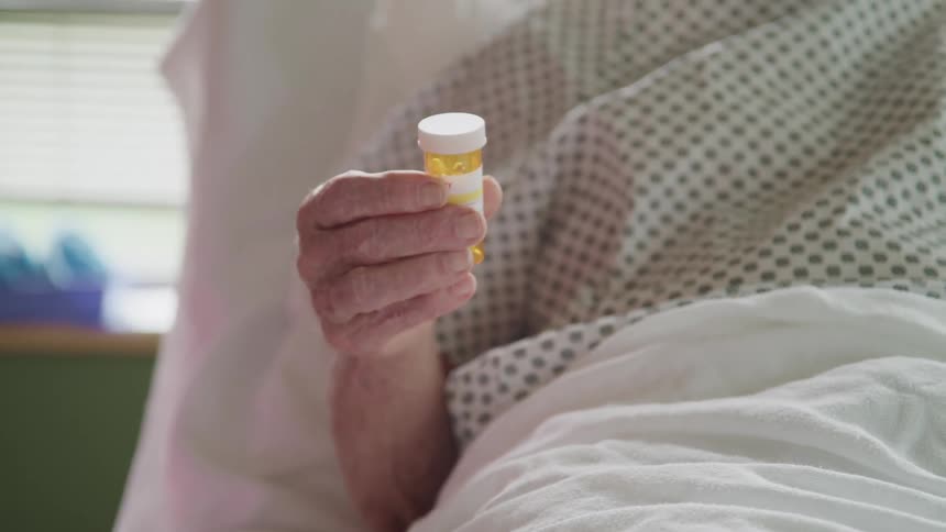 A hospital patient reads instructions on a bottle of medication