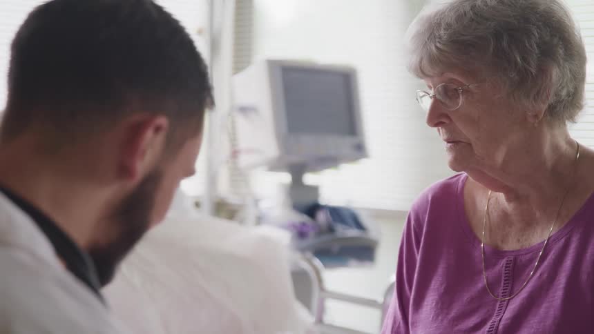 A doctor talks with an elderly woman in a hospital room
