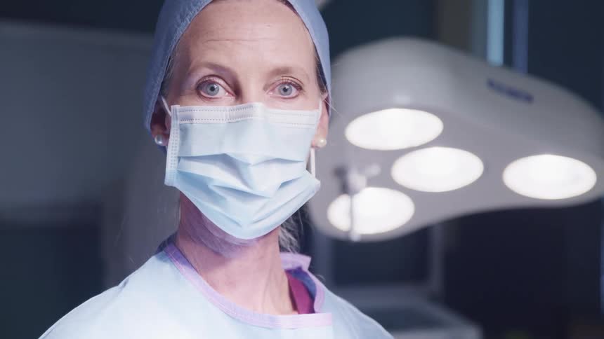 A doctor turns her head up in the operating room