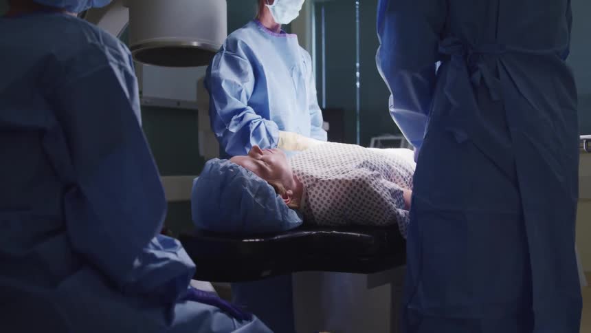 A patient lying on an operating table with doctors and nurses around him