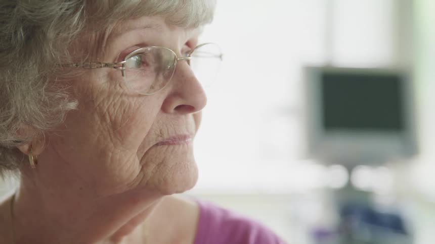 An elderly woman standing and staring in a hospital room
