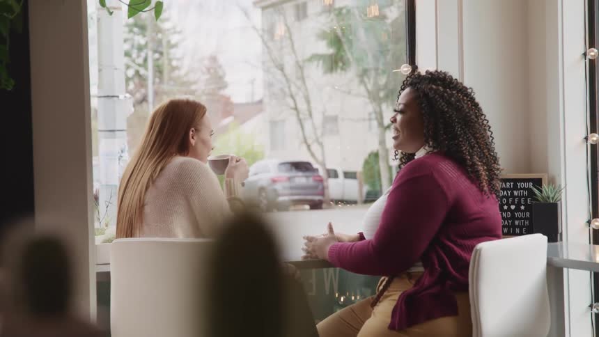 Two females sitting in a cafe chatting and drinking coffee
