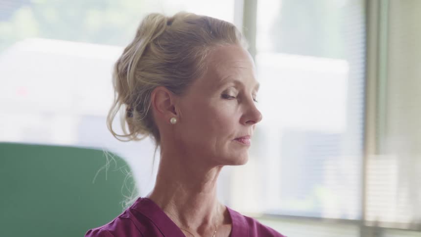 A nurse looks out the window and then turns her head to smile
