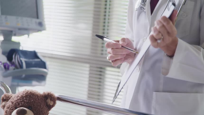 Doctor wearing a lab coat explains something to a patient in a bed