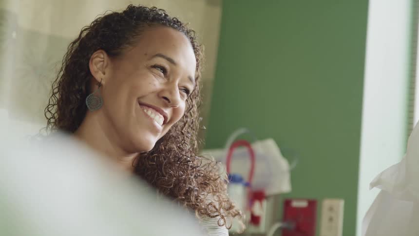 A woman talking and smiling in a hospital next to a window