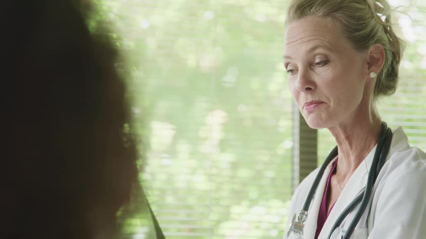 A doctor looks at an xray and discusses it with a patient