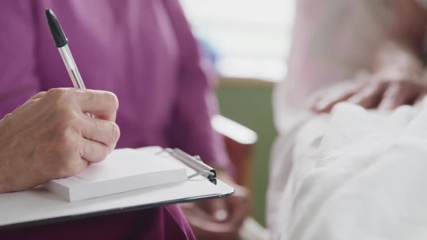 A doctor writes a prescription for a patient in the hospital