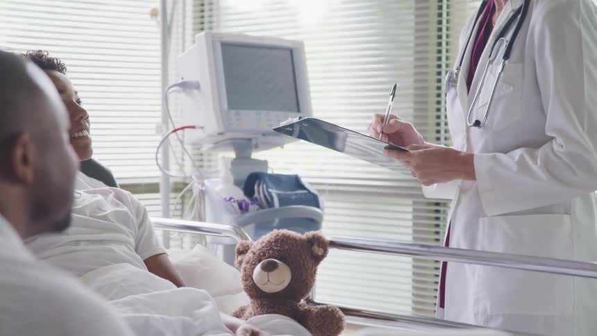 A female doctor writes on a clipboard standing beside her young patient