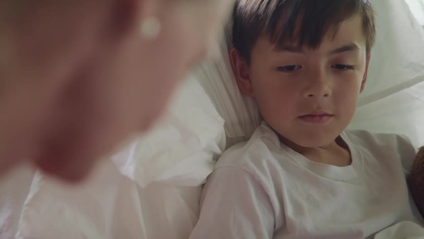A small boy sitting in a bed next to a woman