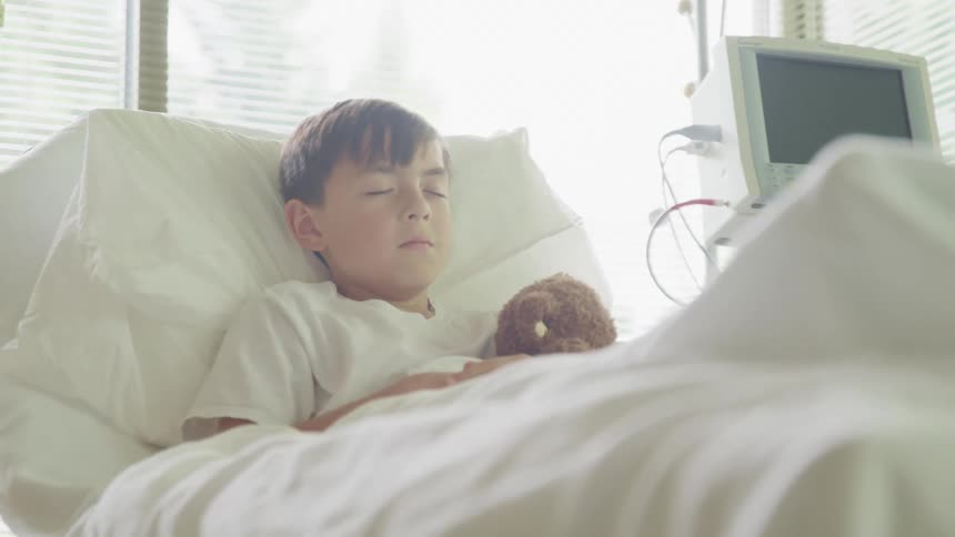 A little boy sleeping in a hospital bed
