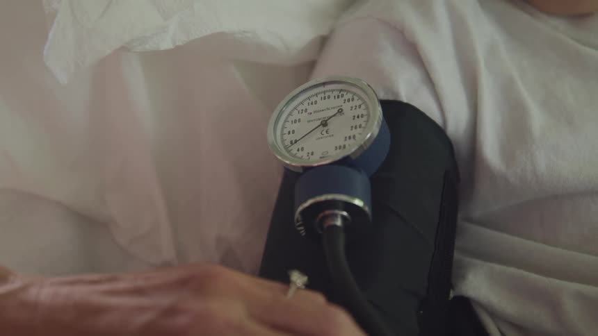 A doctor uses a manual blood pressure cuff on a boy in a hospital bed