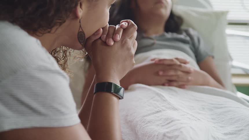 A woman sits near a patient in the hospital