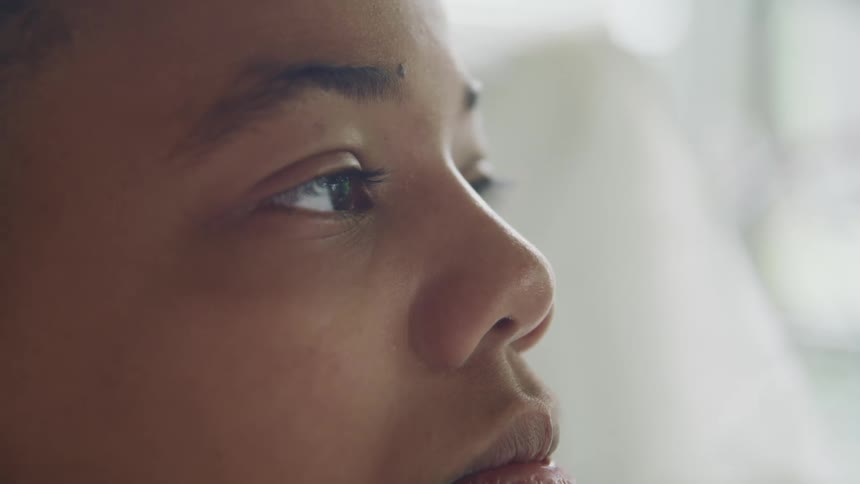 A boy sits in a hospital bed while lost in thought