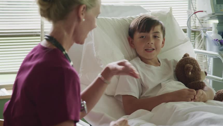 A nurse talks to a little boy in a hospital bed
