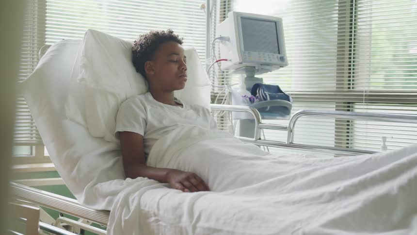 A boy sleeps in his hospital bed