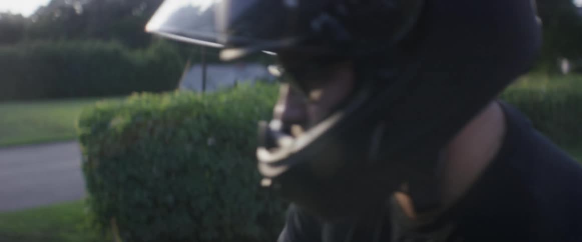 A man secures a helmet and climbs onto a motorcycle