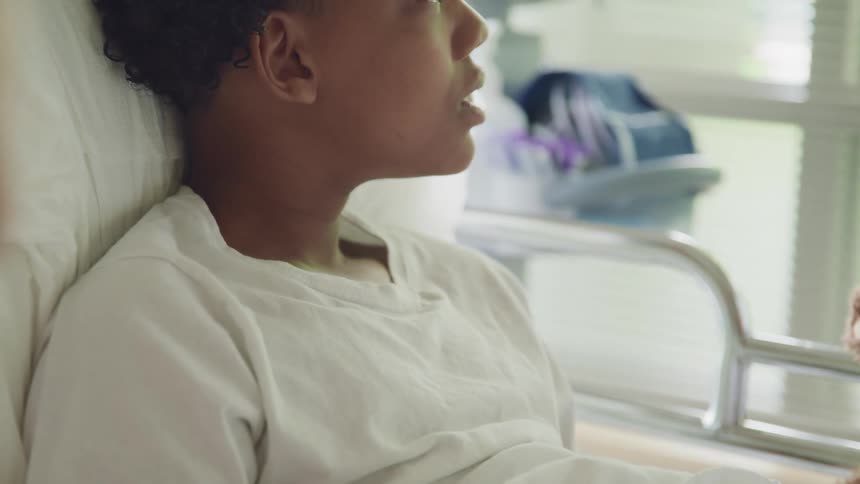 Patient sits up in hospital bed wearing white t shirt