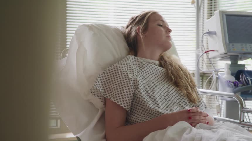 A teenage girl lying in a hospital bed