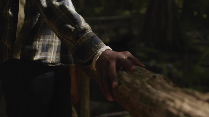 A person leans on a log in the woods