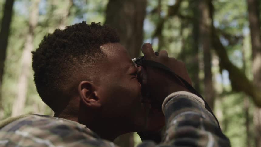 A teenage boy takes photographs in a forest