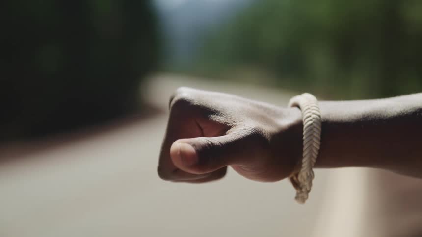 A hitchhiker stands on the side of a road and sticks out his thumb