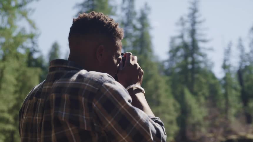 A young man takes pictures in a forest