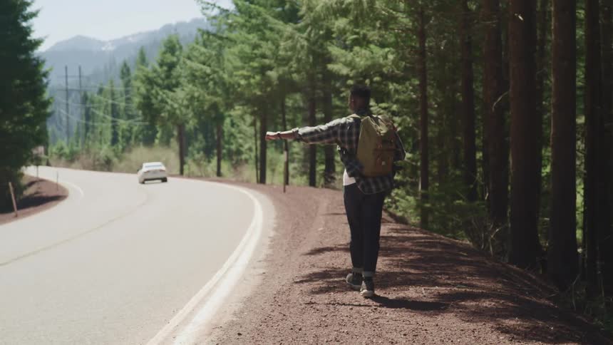 A man is hitchhiking as a car passes