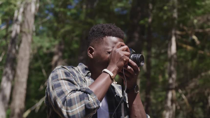 A teenage boy takes pictures in a forest