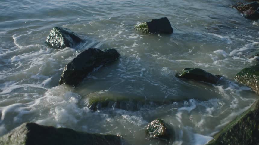 Waves crash into some rocks by the shore