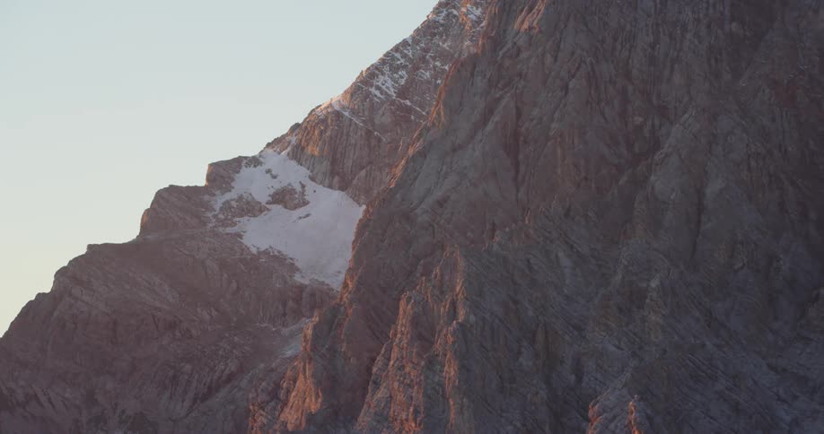 An aerial view of snow dusted mountains at sunrise