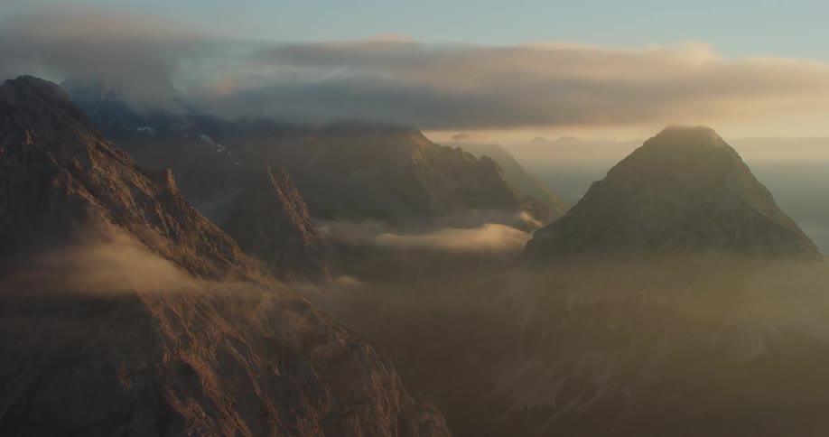A mountain range with sunlight and clouds with the sky in the background