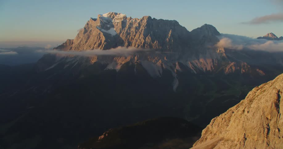 Aerial view of mountain range peaks over the clouds at sunset