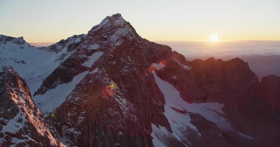 A snow covered mountain summit stands high above a layer of clouds