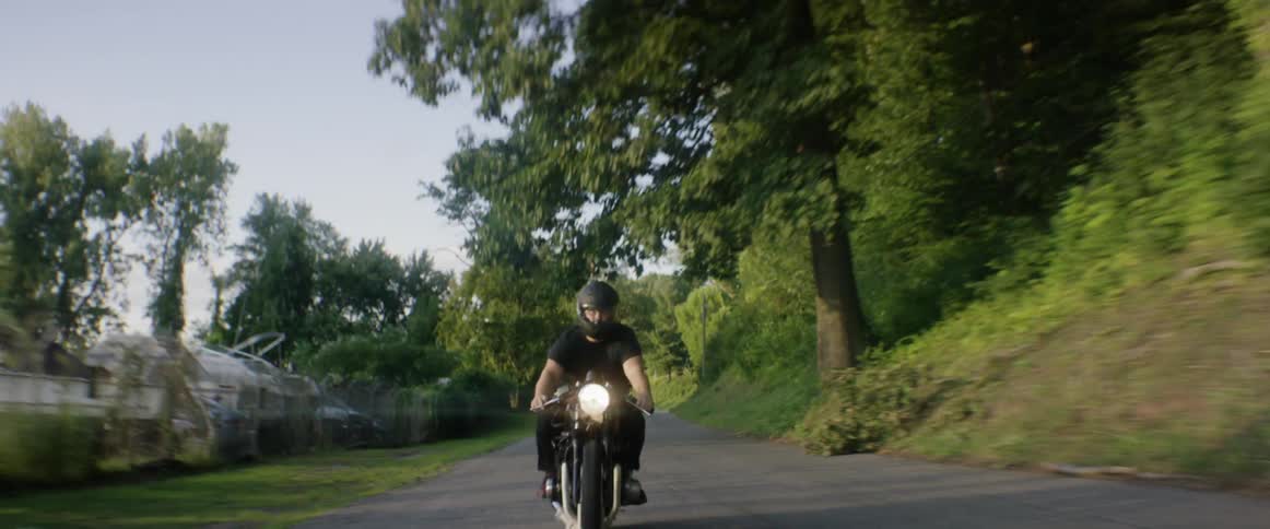 Man riding a motorcycle down a paved rural road