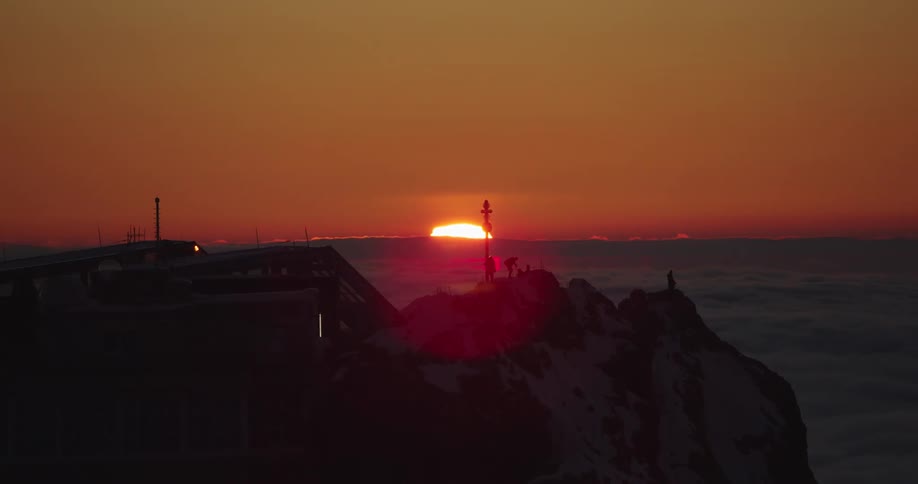 Time lapse of people on a cliff on the coast watching the sunset