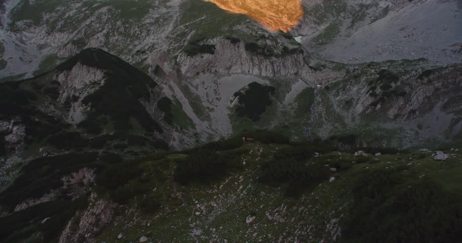 Aerial view of a house near a small lake in the crater on a mountain at sunset