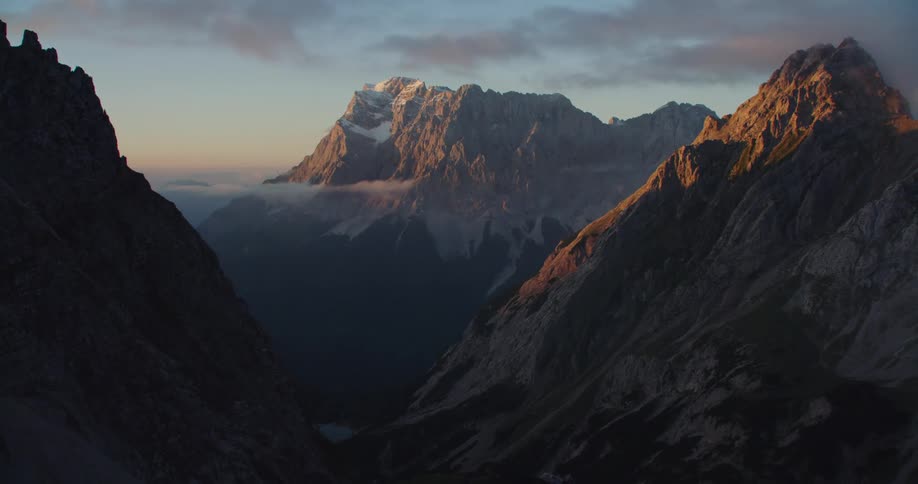Aerial view of the snow covered peaks of a mountain range at sunset