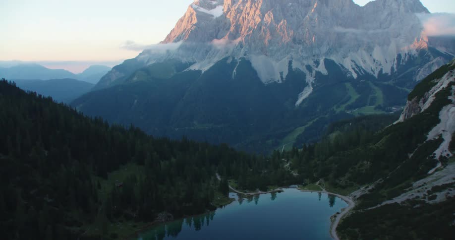 A placid lake is situated along side a trail that passing through a stunningly scenic mountain range
