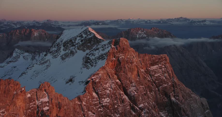 An aerial view of a mountain is displayed while the sun is rising