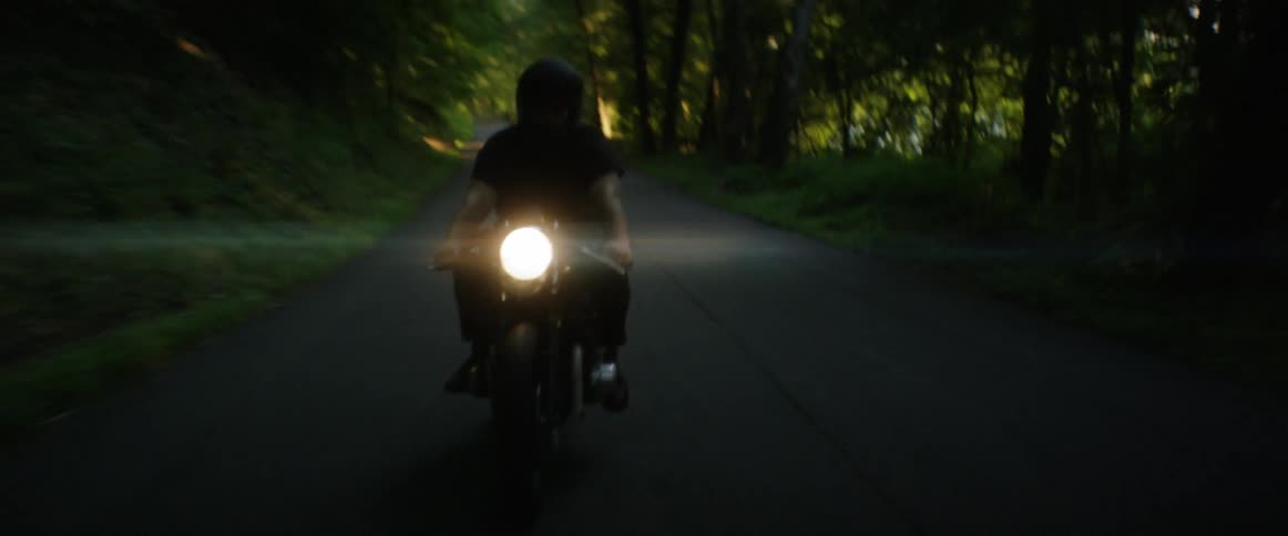 Man riding a motorcycle down a paved rural road