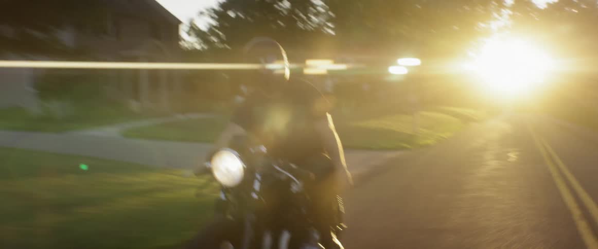 A man rides a motorcycle down a country road