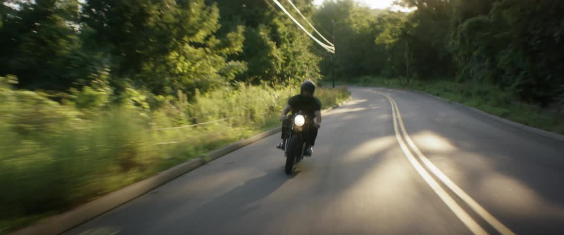 A man in a black shirt rides his motorcycle in the street