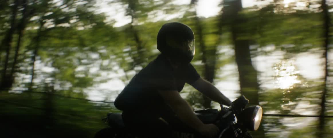 A man rides a motorcycle down a country road