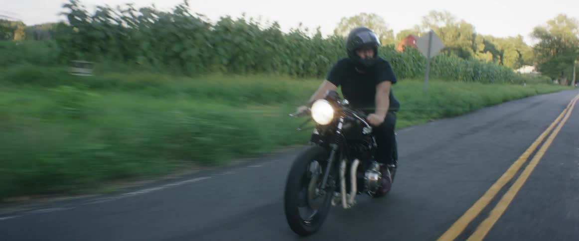 A man driving a motorcycle along a country road
